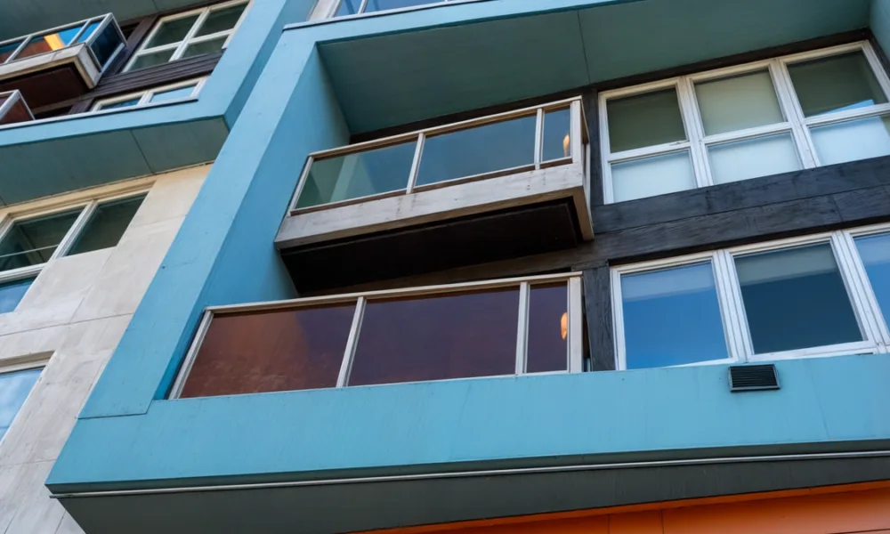 Comparison between reflective glass and tinted glass façades showing differences in solar reflection, color tone, and exterior appearance in modern architecture.